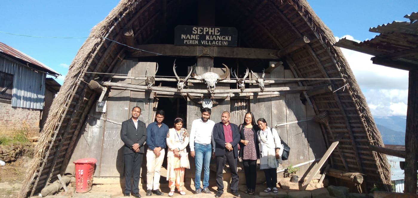 Paritosh Bag with fellow travellers in front of a traditional thatched morung at Peren village, Nagaland